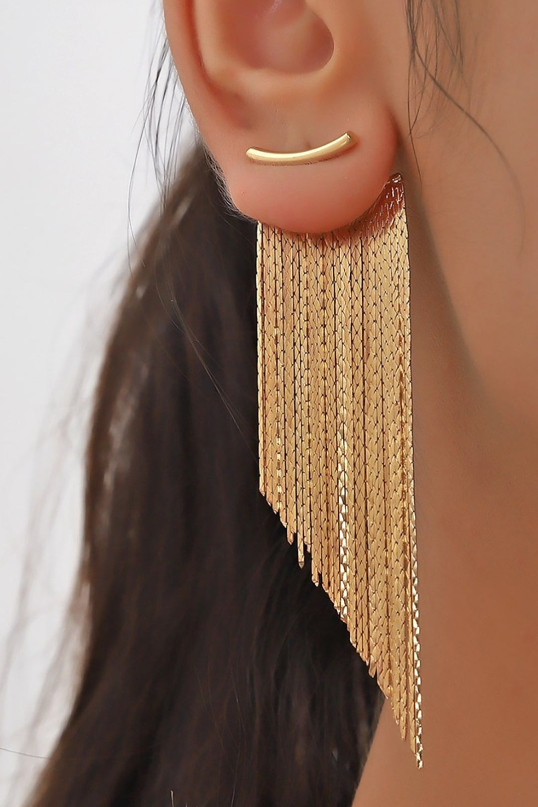 Asymmetrical metal fringe earrings with cascading gold and silver strands on a soft fabric background