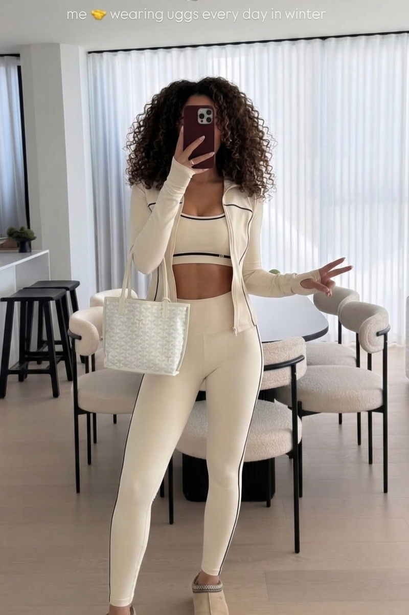 Woman in a white outfit taking a mirror selfie in a modern interior setting.